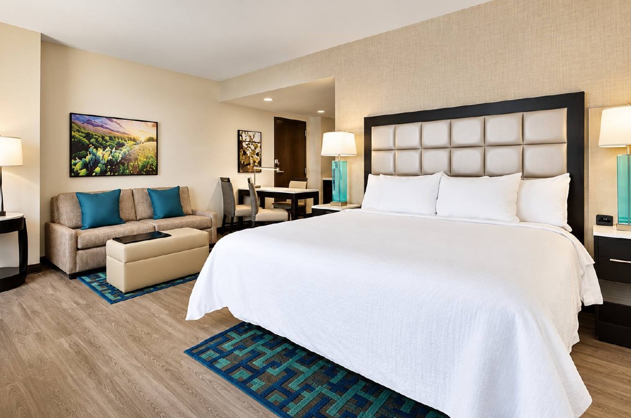 Embassy Suites guest suite with king bed, sofa and dining area